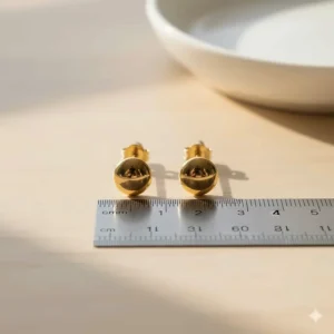 Image demonstrating the size of the 14k gold stud earrings next to a ruler or coin for scale.