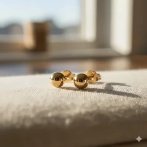 A pair of classic, polished round tiny 14k gold stud earrings with a butterfly back.