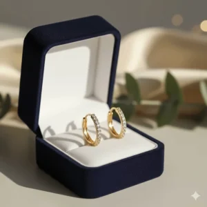 A pair of gold diamond huggie earrings tucked inside a velvet jewelry gift box.