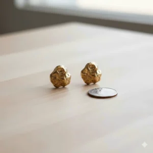 The 10k gold nugget earrings placed next to a common object (like a coin) to clearly show their actual size.