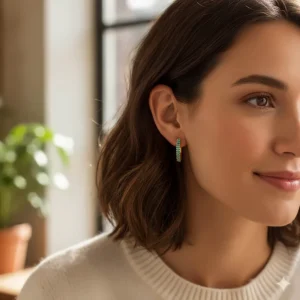 Close-up of a woman wearing gold gemstone earrings in a hoop style with small turquoise accents.