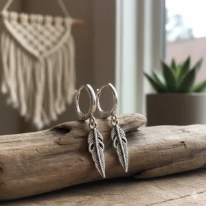 Bohemian-inspired huggie earrings with delicate silver feather charms hanging from the hoops.