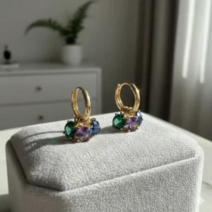 Vibrant huggie earrings with emerald and sapphire gemstone charms set in polished 14k gold.