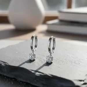 Luxury sterling silver huggie earrings featuring a single sparkling diamond solitaire charm.