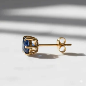 Side profile view of a gold sapphire stud earring showing the secure butterfly back and prong detail.