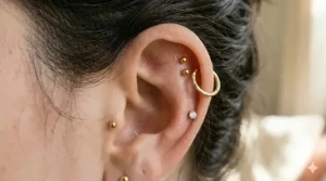 A double helix piercing featuring matching dainty gold studs for a stacked earring look.