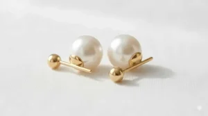 Pair of front back pearl earrings featuring 14k gold posts and polished white pearls.