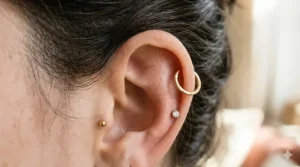 A minimalist gold seamless hoop earring styled in a mid-helix piercing.